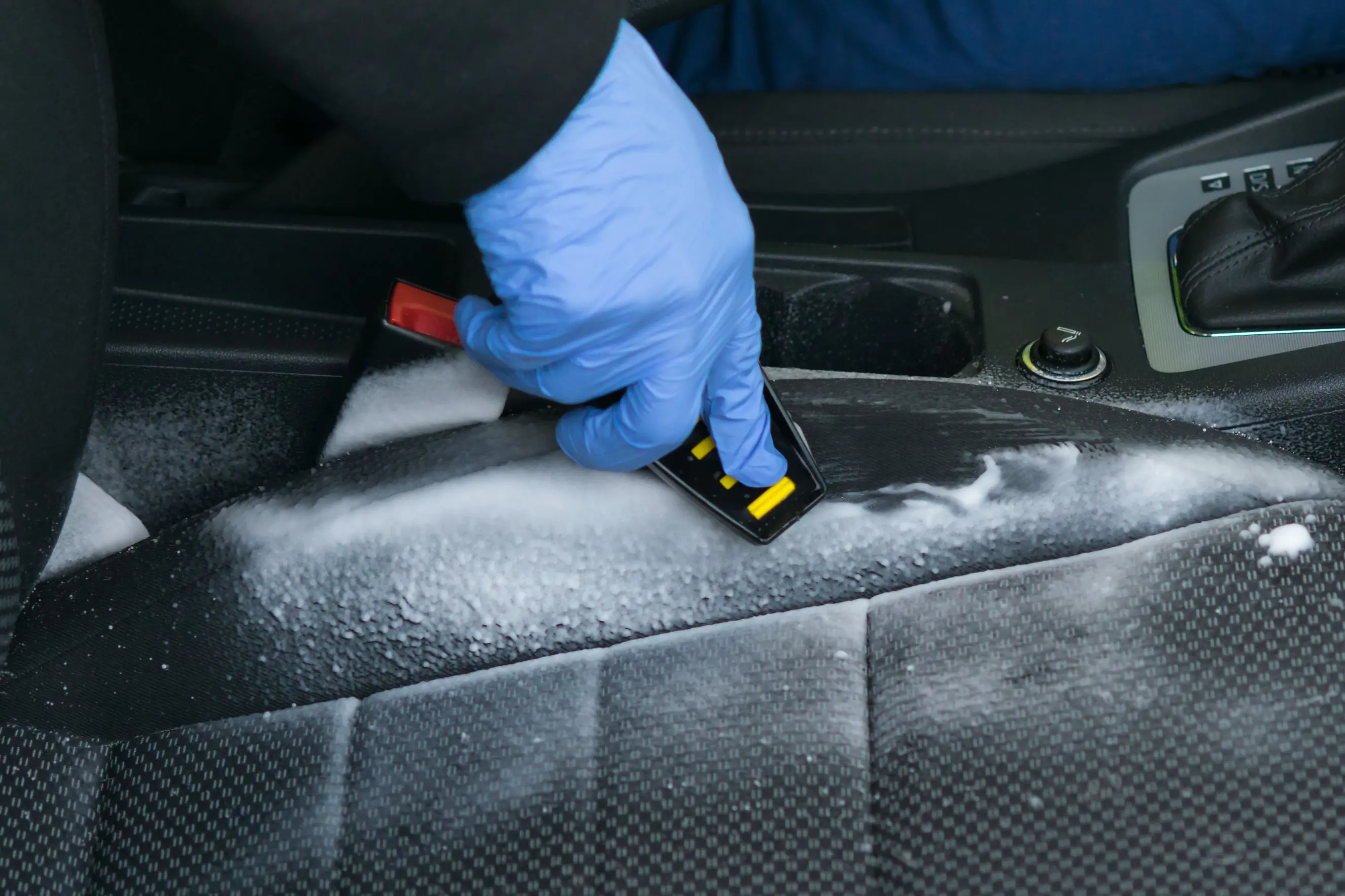 Cleaning car seat with brush and foam.
