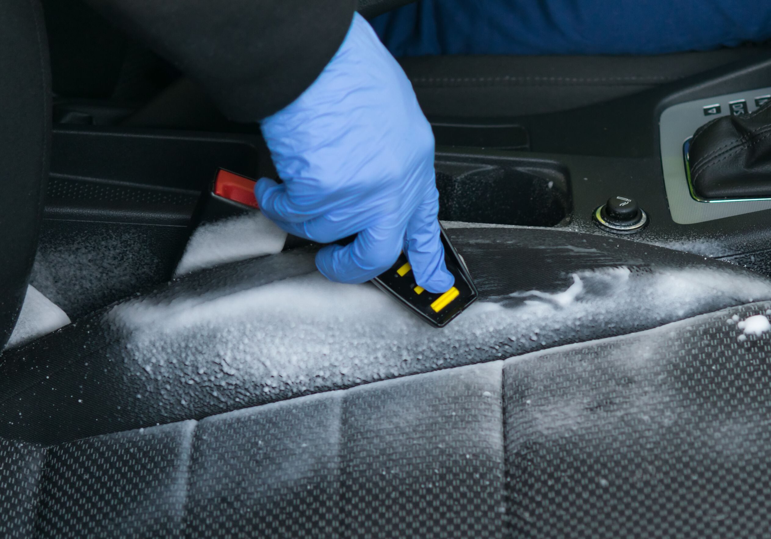 Cleaning car seat with brush and foam.